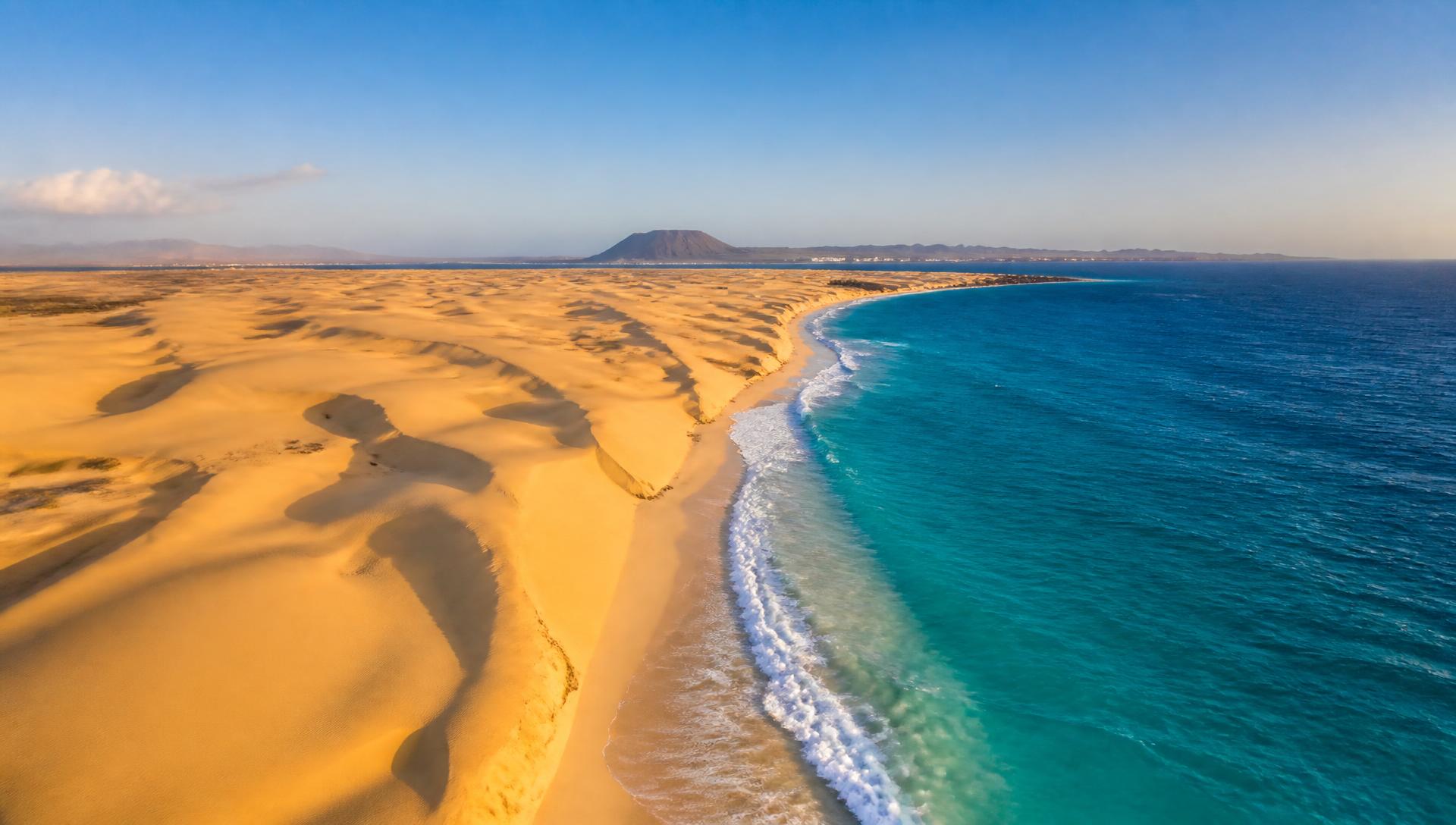 Dunas doradas del Parque Natural de Corralejo junto al océano turquesa, Fuerteventura